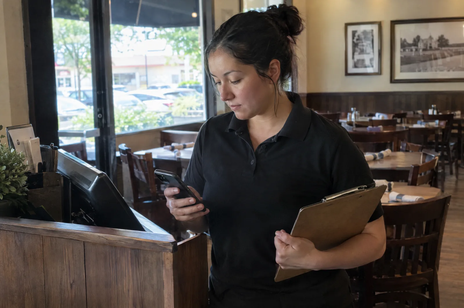 A manager at the host stand reading an alert on her phone